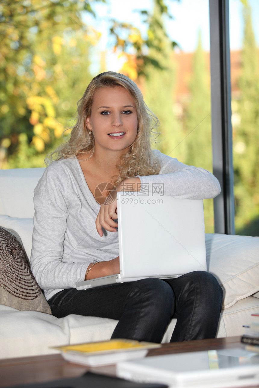 金发女孩用笔记本电脑坐在家里图片