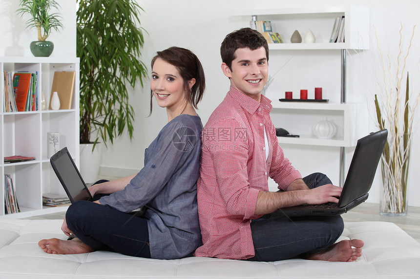 几对坐在背靠背的一对夫妇 在他们的笔记本电脑上工作图片