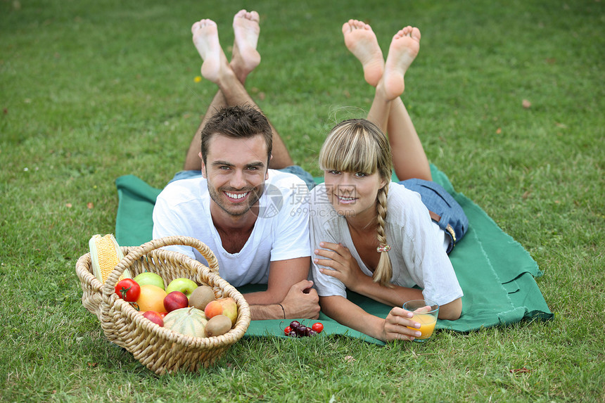 夫妻在公园享受野餐水果阳光男人幸福草地闲暇篮子果汁食物恋人图片