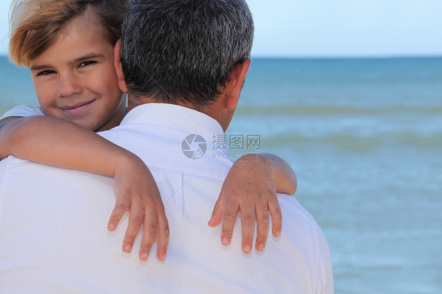 一个父亲在海滩上拥抱他的儿子图片
