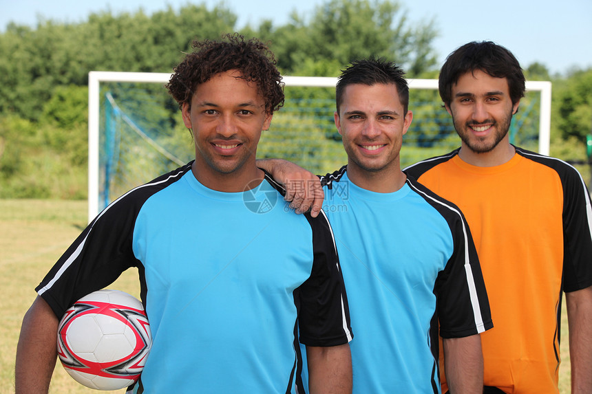 三名微笑的足球运动员在球门前图片