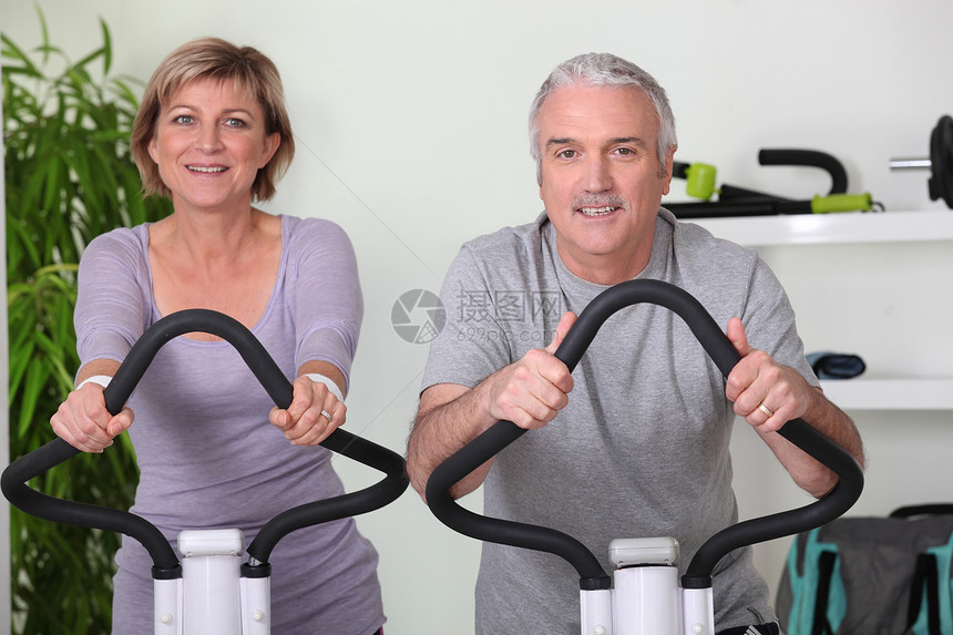健身房的高级夫妇骑自行车图片