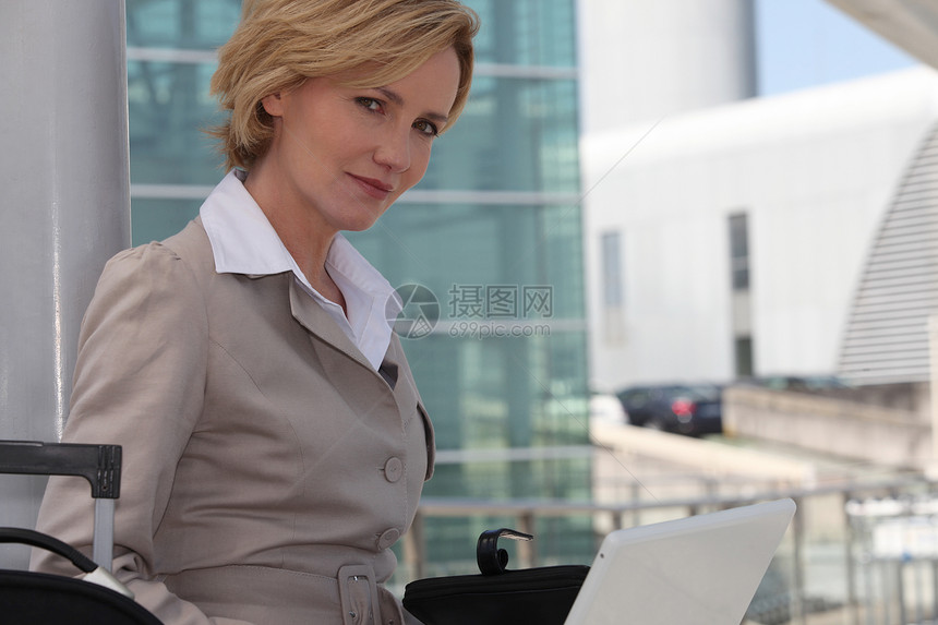机场外膝上型电脑上的女商务人士女性经理套装管理人员飞机场白色销售量导演金发女士图片