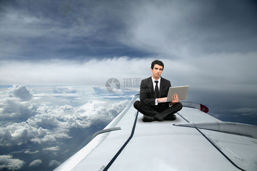 商务人士坐在飞机的机翼上图片