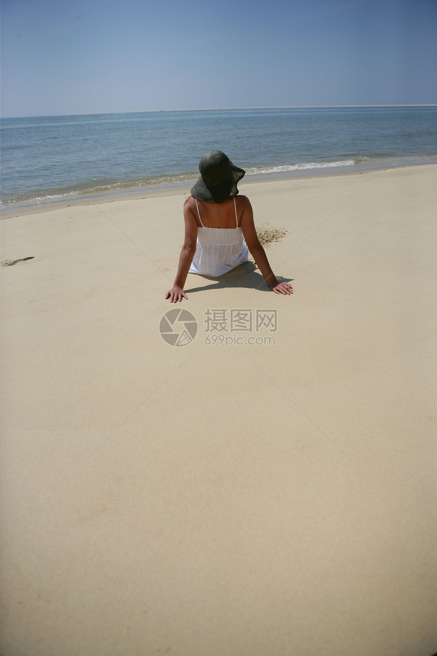 坐在沙滩上的女人旅行女士日光浴海岸线太阳稻草阴影假期蓝色女性图片
