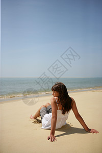女人坐在荒无人烟的沙滩上背景图片
