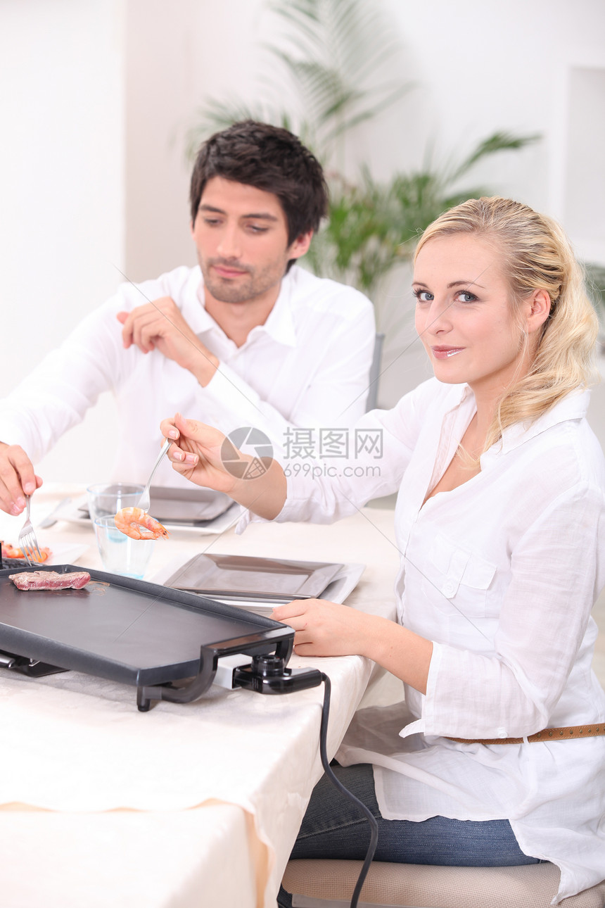 一对夫妇在桌面电盘上煮肉图片