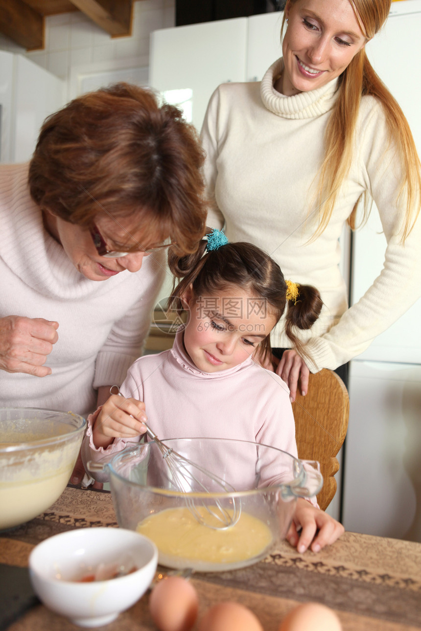 小女孩和她妈妈和奶奶一起烘烤图片