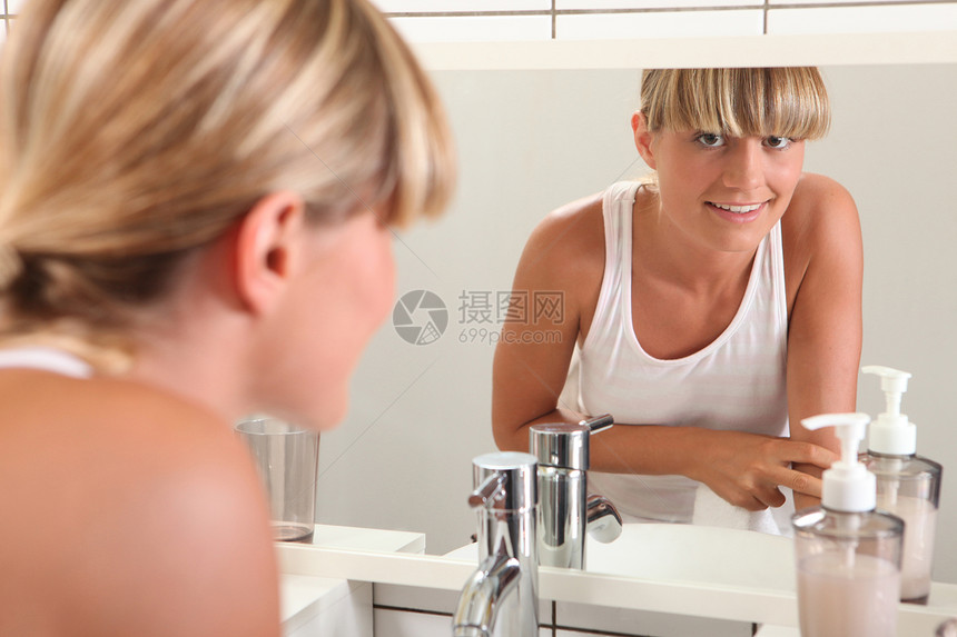 年轻女人看着浴室镜子的女青年图片