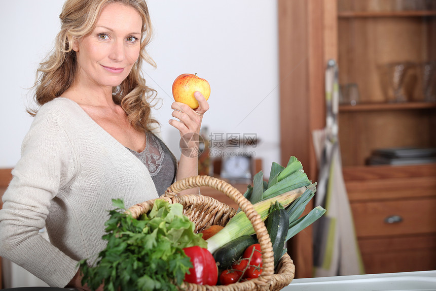 妻子拿着苹果幸福女性食物微笑蔬菜金发白色篮子厨房头发图片