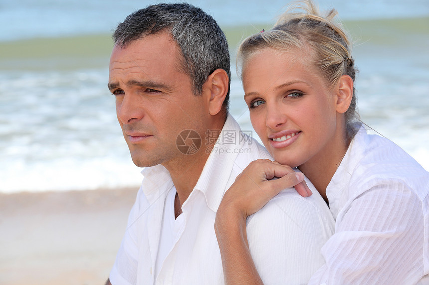 穿着白衣的夫妇站在沙滩上图片