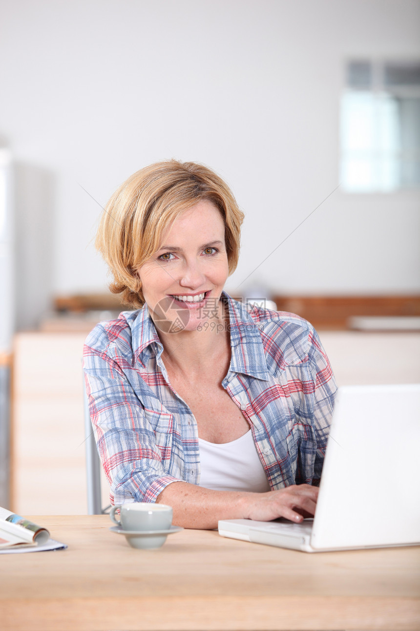妇女用笔记本电脑在厨房打字图片