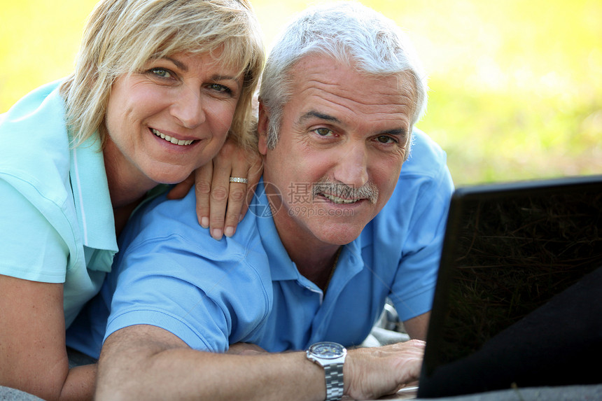 微笑的成熟夫妇与户外笔记本电脑的肖像图片