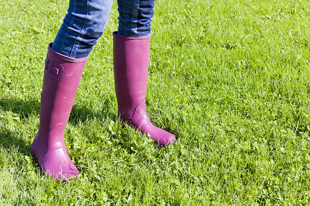 靴子详情女性在草坪上穿着橡胶靴子的详情外观裤子牛仔裤鞋类成人牛仔布紫色草地女士背景
