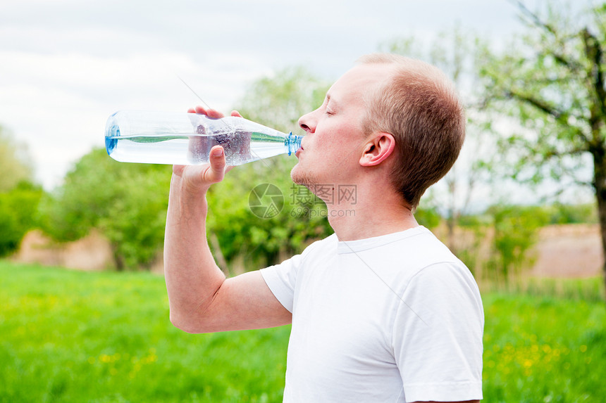 年轻Jogger在户外饮用饮水液体训练瓶子赛跑者成人行动运动跑步男性慢跑者图片