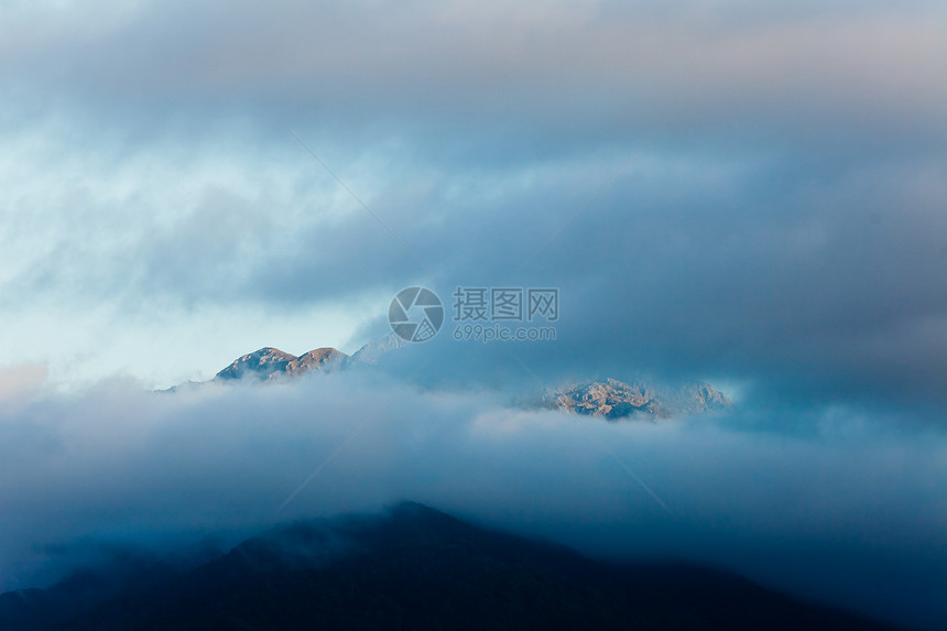 高崎岖山峰上的黑日落云图片