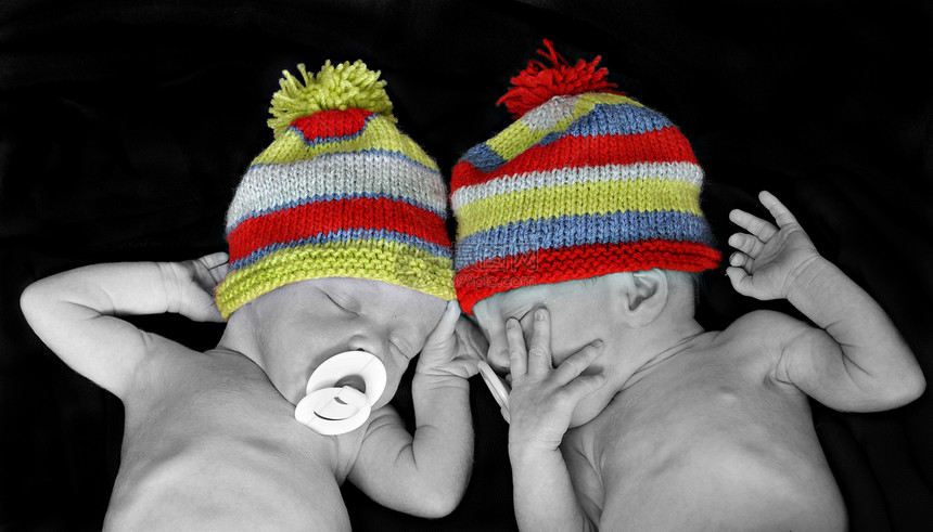 新出生的双胞胎 戴多彩色条纹帽子图片