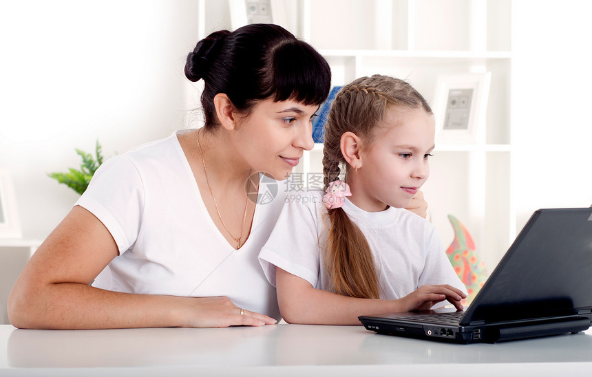 妈妈和女儿一起为笔记本电脑工作女士冲浪互联网父母童年女孩们闲暇母亲办公室技术图片