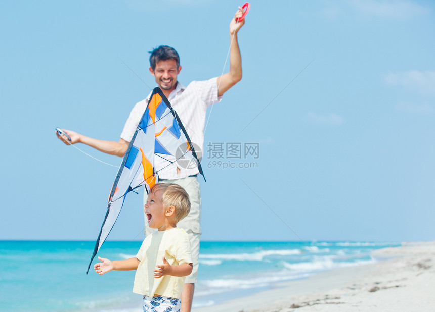 男孩和父亲在海滩上玩风筝闲暇娱乐男生快乐孩子们乐趣青年蓝色晴天空气图片
