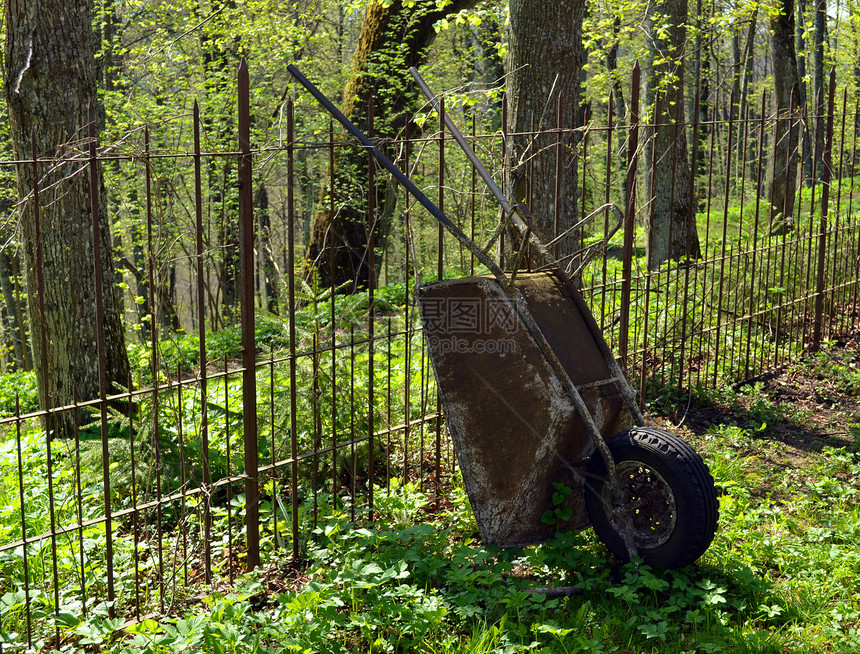 旧的生锈花园工具轮式手推车金属栅栏图片