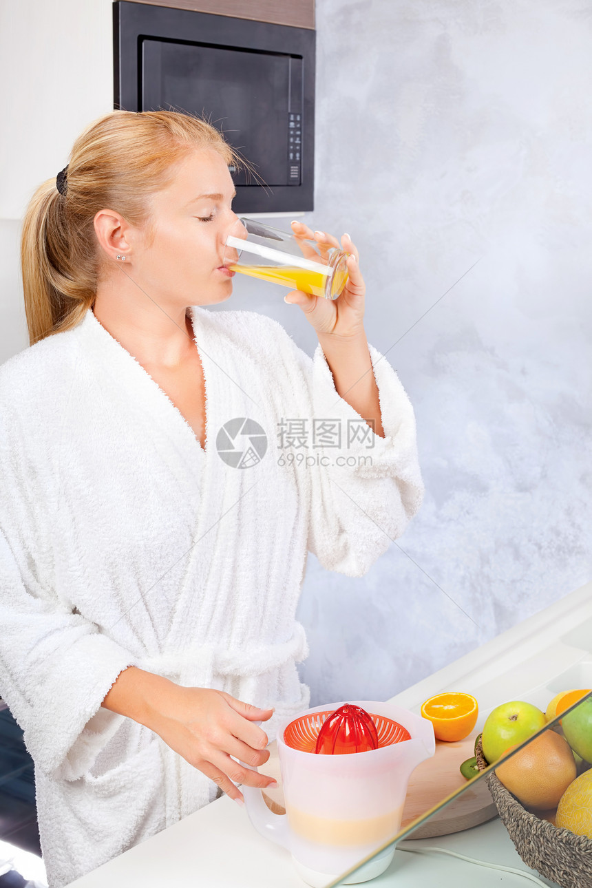 妇女在厨房喝新鲜果汁图片