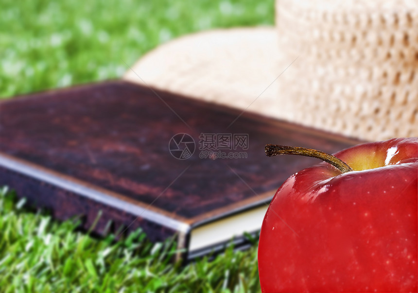 外面草地上的苹果书和帽子图片