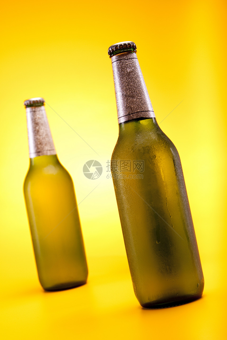 黄色背景的冷冻啤酒饮料琥珀色液体茶点玻璃瓶子棕色派对气泡冷藏图片