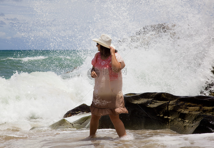 戴白帽子的女士是海滩上的波浪图片