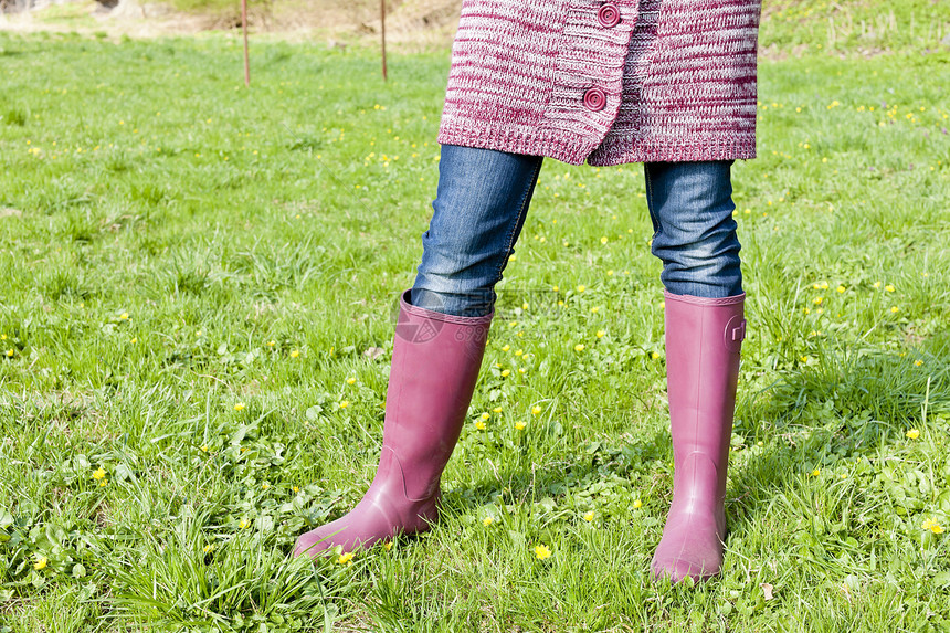 妇女穿着橡胶靴在春草草地上穿橡皮靴的情况女士外观成人牛仔裤女性裤子鞋类紫色牛仔布毛衣图片
