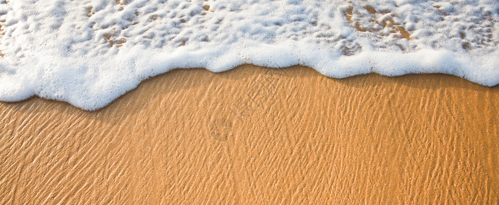 波浪在沙滩上涌起热带泡沫日落海浪背景图片