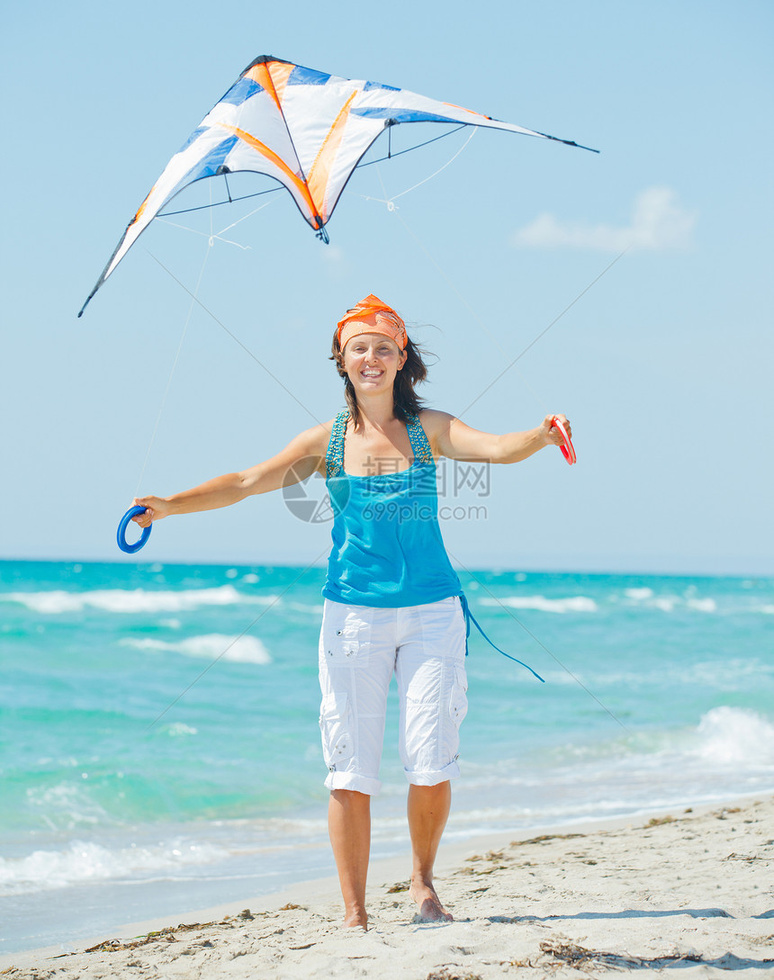 海滩上的女人玩着多彩的风筝童年青年女士蓝色空气孩子幸福天空享受女孩图片