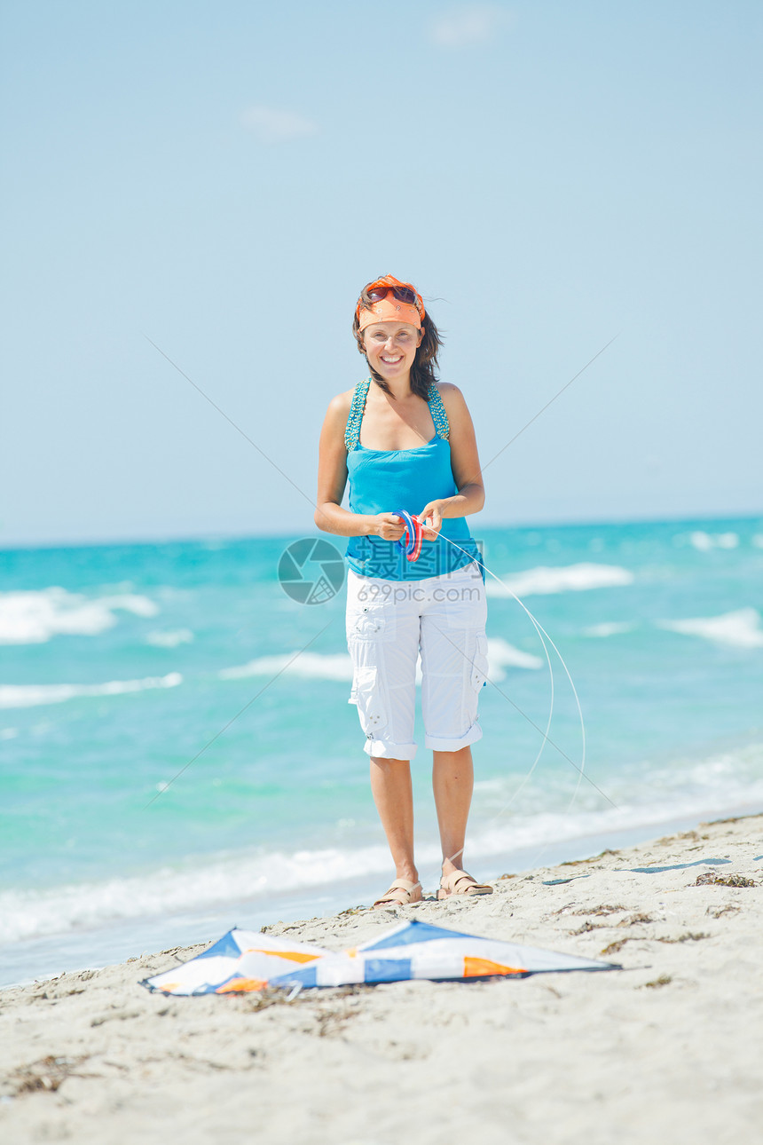 海滩上的女人玩着多彩的风筝女士乐趣娱乐喜悦晴天孩子运动热带活动蓝色图片