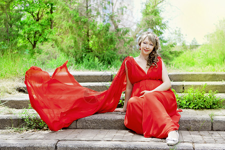 穿红裙子的孕妇坐着背景图片