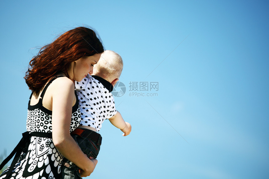 母亲和儿子微笑快乐乐趣天空太阳父母男性蓝色幸福童年图片