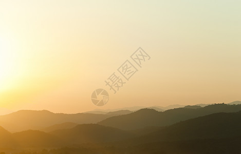 日落在山后面地形地平线黄色山脉阳光光线薄雾场景背光橙子背景图片