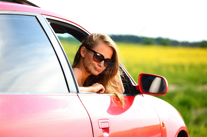 妇女乘坐红色车汽车金发女郎玻璃头发女孩司机快乐销售青年运动图片