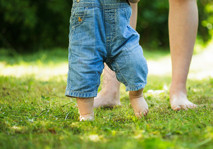 最初步骤帮助女儿育儿牛仔裤高度父母脚步女士家庭赤脚背景