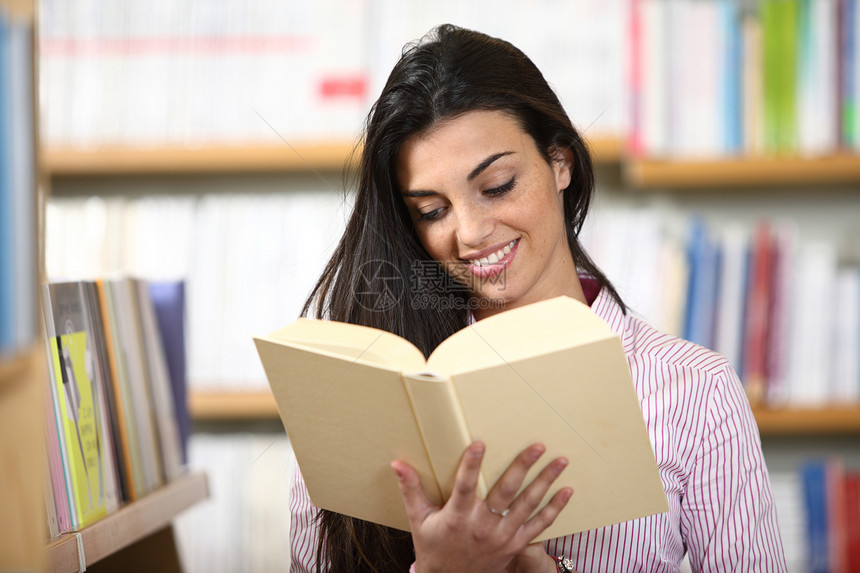 书在书店里手头拿着书籍 微笑着笑着的女学生店铺书柜教育学习校园女孩文学书架知识科学图片