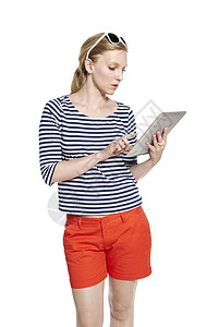 使用平板药的年轻妇女短裤双手互联网头发橙子衬衫大学生女士太阳镜影棚背景图片