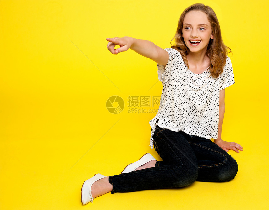 微笑的年轻女孩向远方指着服装地面魅力青少年黄色青年手指冒充女性快乐图片