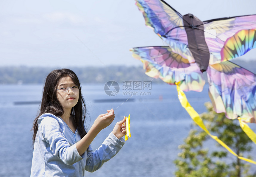 在湖边放风筝的比种族和亚裔女孩蓝色绿色风筝混血飞行女性孩子晴天活动图片