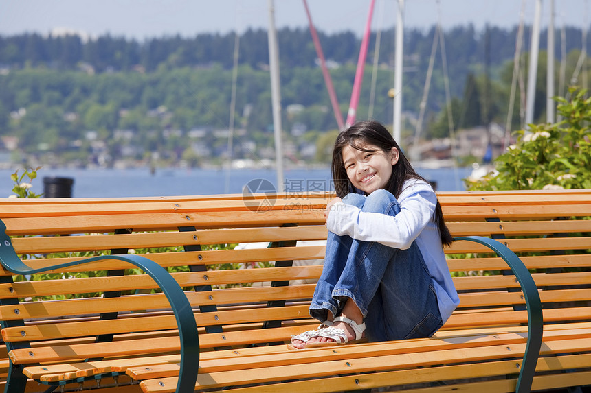 十岁女孩在湖边的长凳上享受阳光图片
