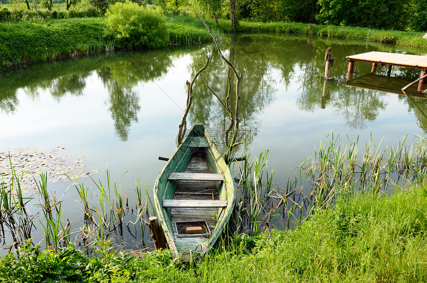 停在池塘岸桥上的旧木船架图片