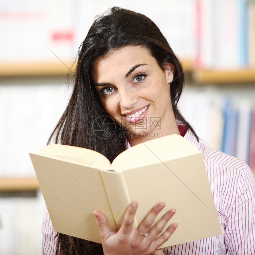 手拿书在书店微笑的女学生  模特文学书架学生女孩女士图书馆学习大学店铺校园图片