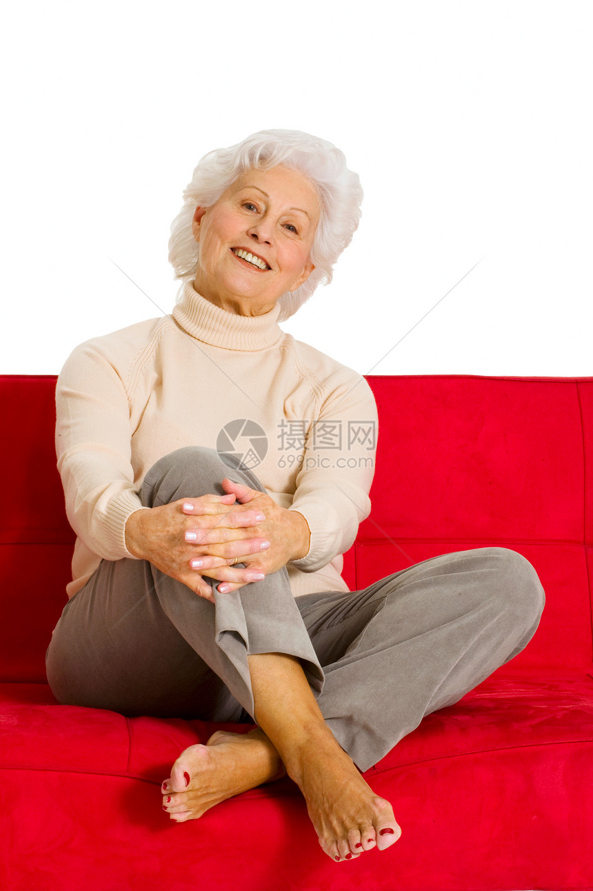 老年妇女在沙发上放松微笑红色家庭生活幸福休闲装赤脚白色图片