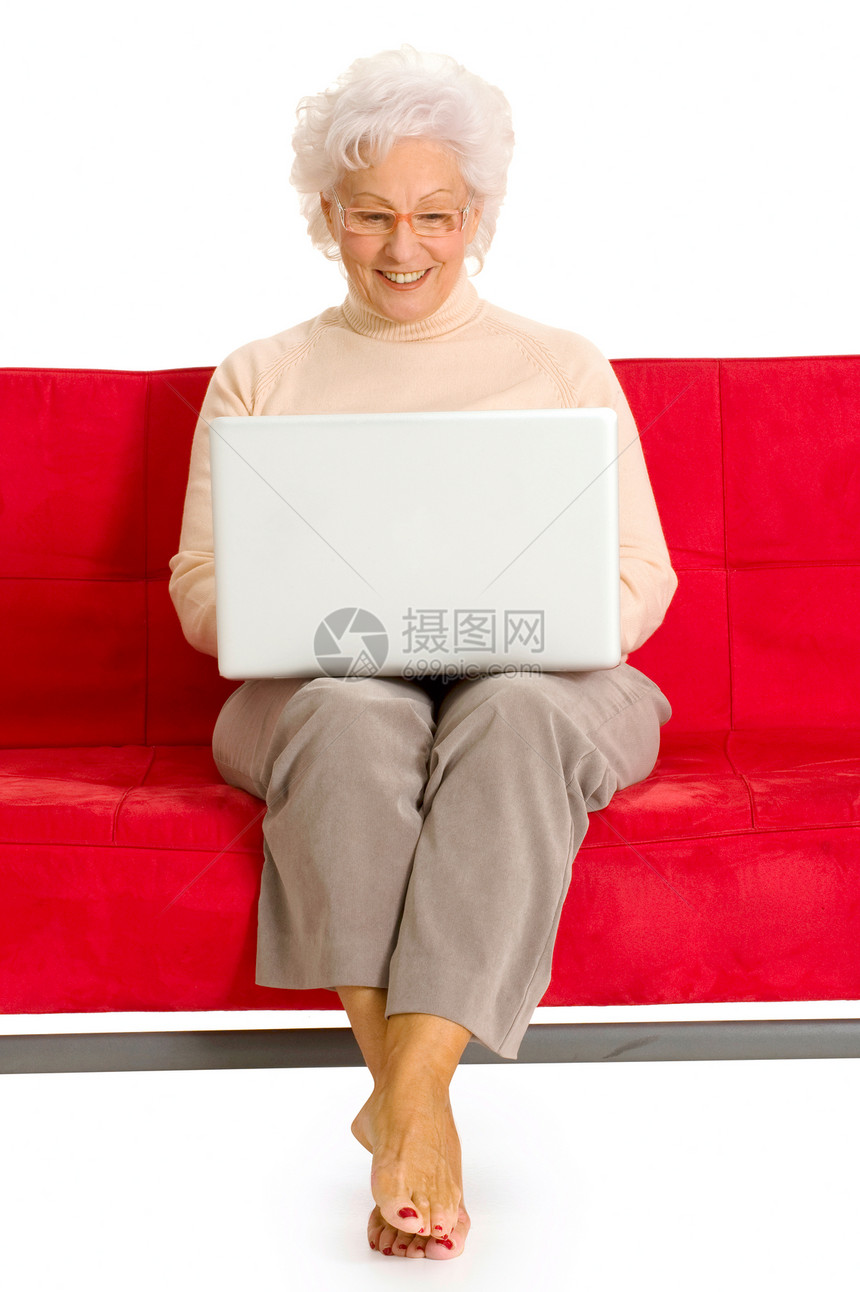 用笔记本电脑坐在沙发上的老年妇女按摩家庭生活白色眼镜红色技术通讯微笑咨询工具图片