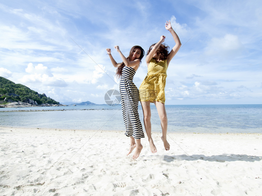 女人一起跳到沙滩上 蓝天背景的蓝色天空背景图片