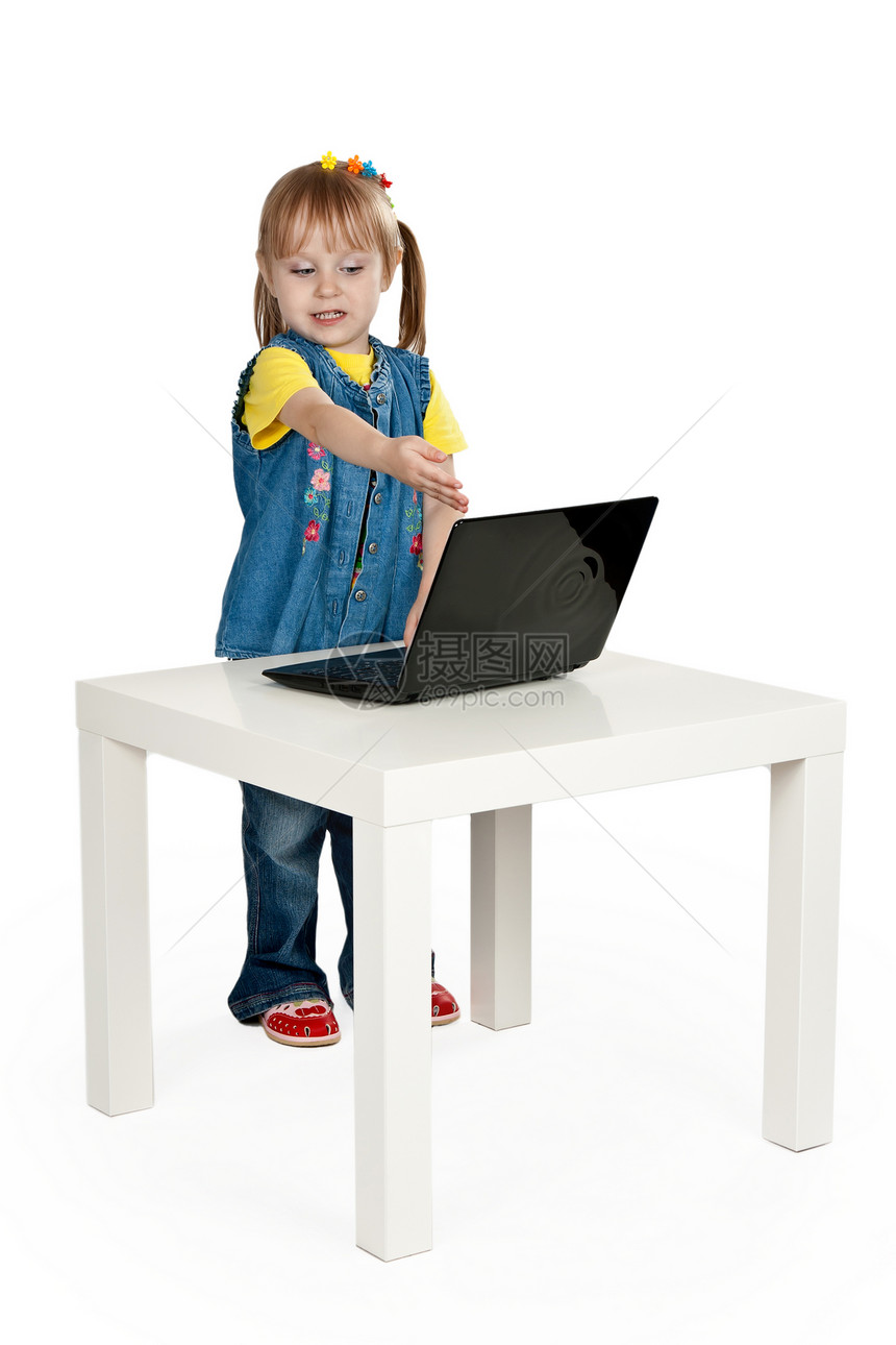 坐在桌子上拿着笔记本电脑的小女孩图片