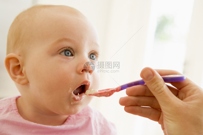 母亲喂婴儿食物给婴儿女性饮食勺子家长微笑家庭妈妈厨房两个人食品图片