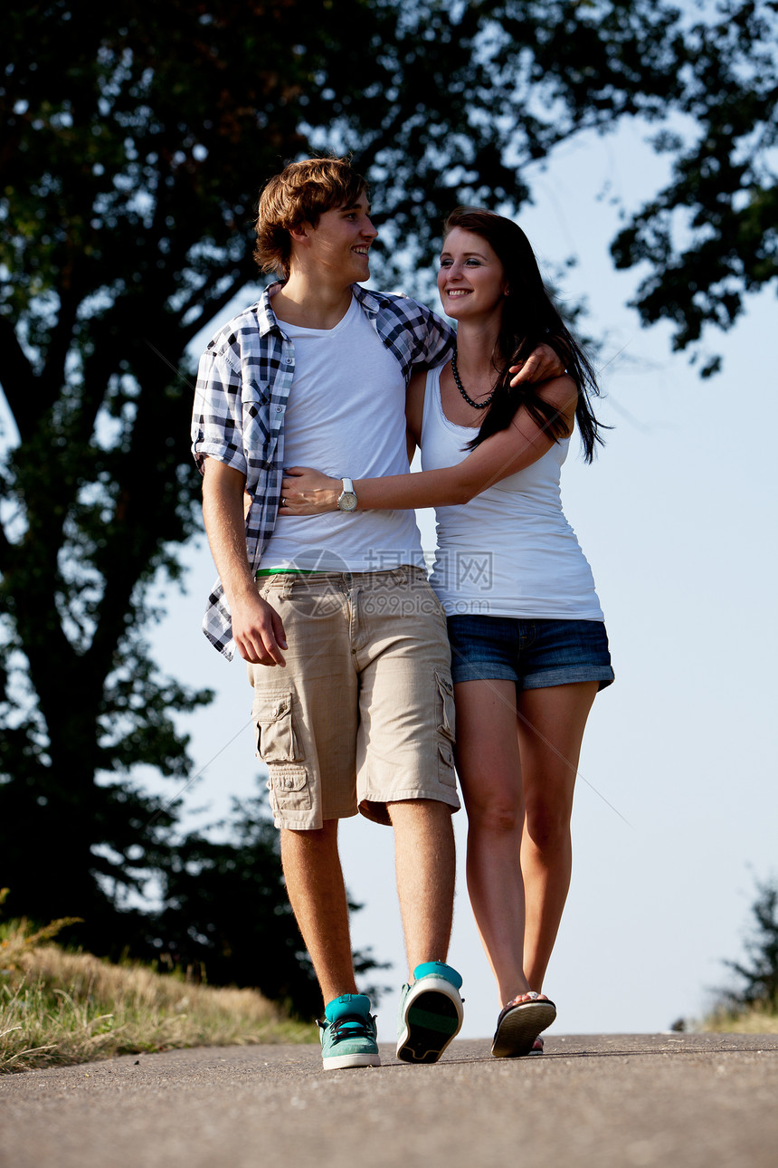 男女青年在夏季户外的一条公路上行走夫妻公园喜悦娱乐女士人行道享受自由幸福场景图片